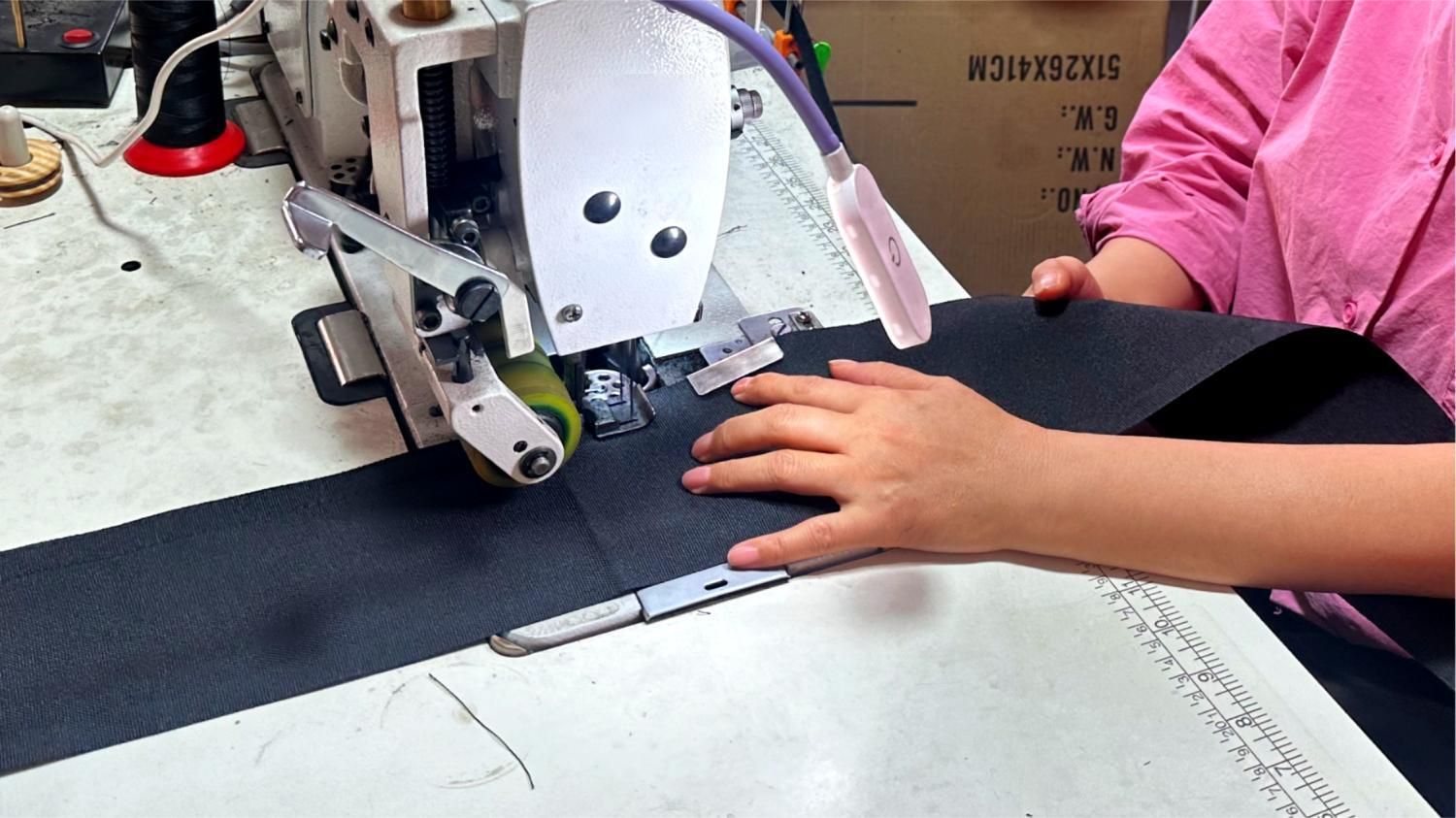 Workers use industrial sewing machines to sew black cable sleeves. Workers use industrial sewing machines to sew black cable sleeves.