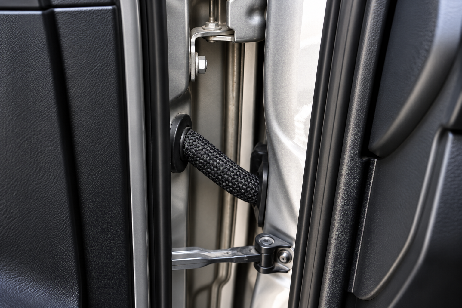 Black PET braided sleeving protecting sensor cables at an automotive hinge point
